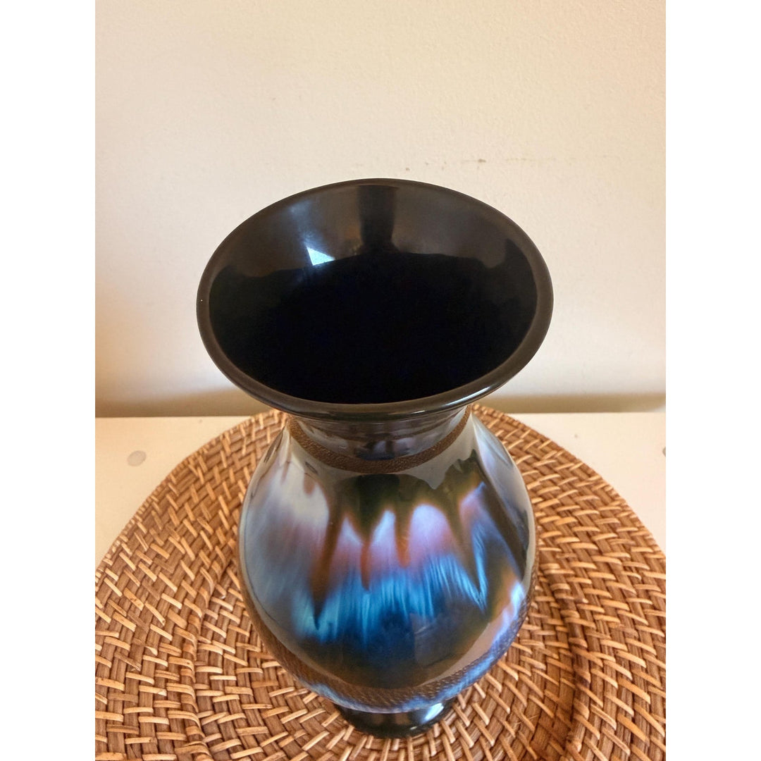 Vintage Rainbow Ceramics vase with blue, teal and copper drip glaze over black, an elongated rounded body, flared opening and pedestal base.