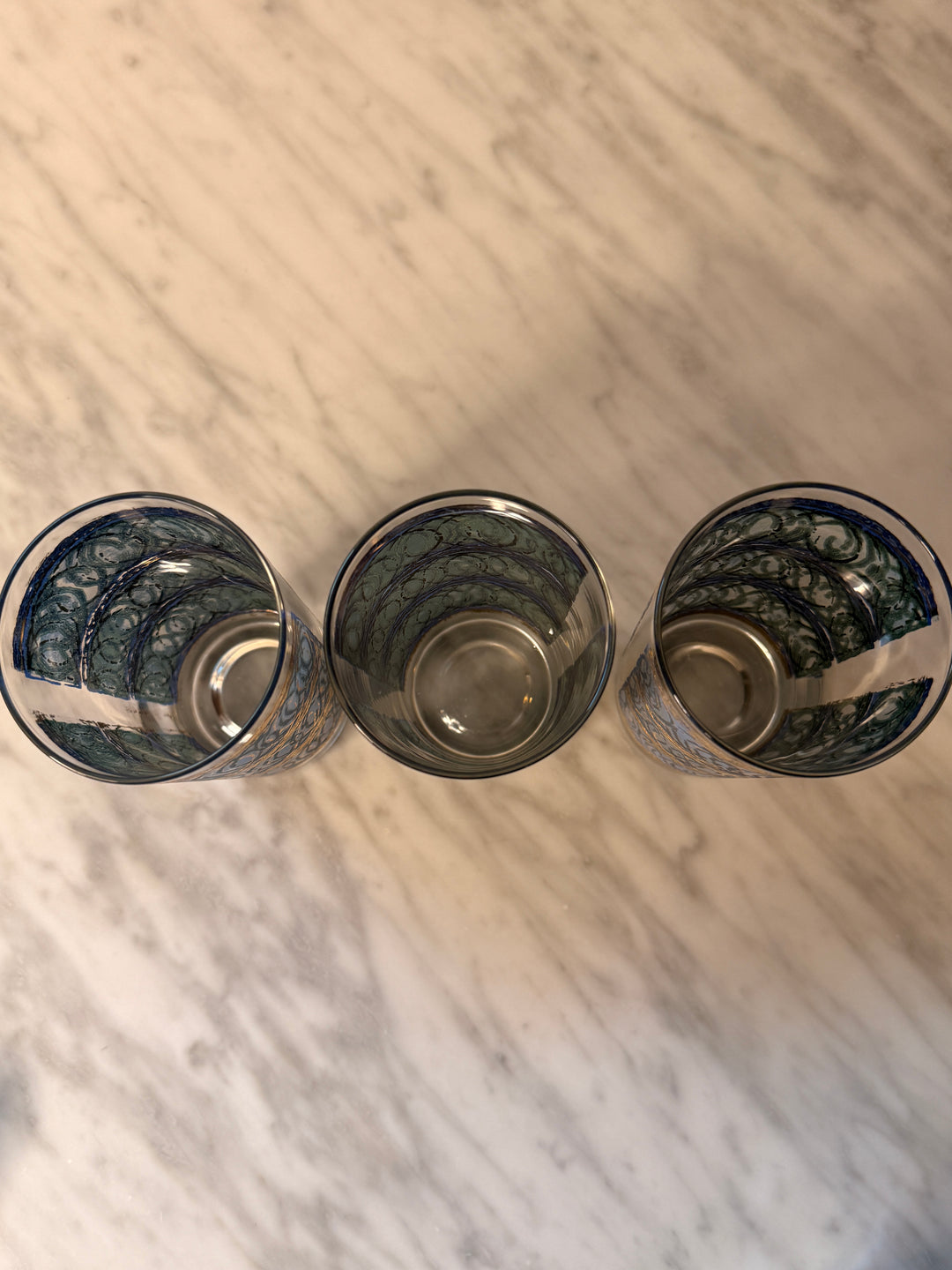 Three vintage Georges Briard highball glasses with blue interlocking oval patterns and 22-karat gold detailing.