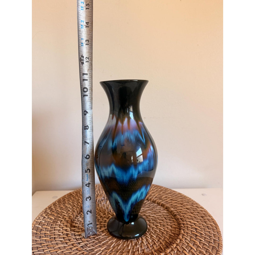 Vintage Rainbow Ceramics vase with blue, teal and copper drip glaze over black, an elongated rounded body, flared opening and pedestal base.